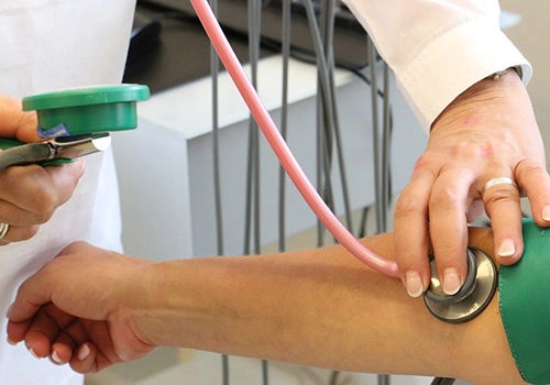 foto mostra medição de pressão arterial, com close nas mãos do profissional de saúde